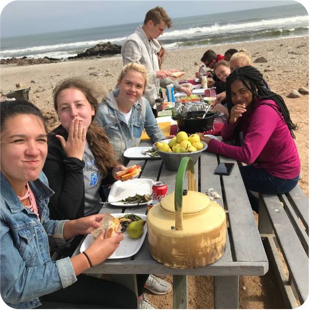 Students at a picnic table in front of water during study abroad trip to Namibia